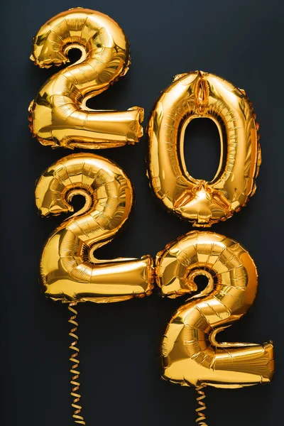 2022 anno palloncino d'oro su sfondo nero con nastri d'oro. Felice anno nuovo invito vigilia con palloncini foglio d'oro di Natale 2022 testo verticale gift card — Foto Stock