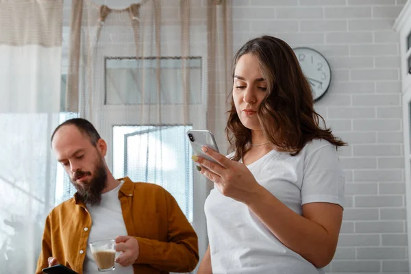 Sad Angry young married couple after conflict fight ignoring each other at home interior. Angry fury woman use smartphone. Man has phone addiction. — Stock Photo, Image