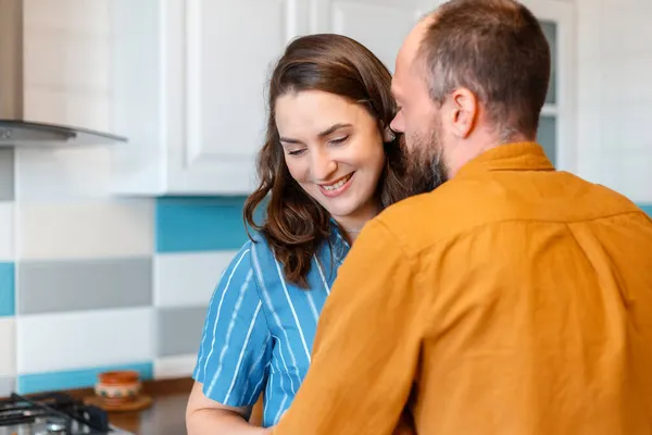 Happy young loving couple man woman 30s in kitchen at home. Married couple Wife and husband hugging having fun Smiling kiss In kitchen interior of apartment. — Stock Photo, Image