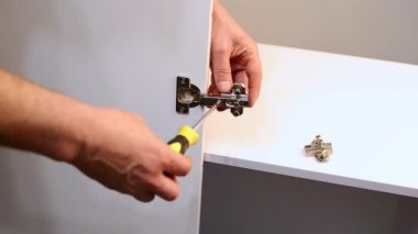 Yeni mobilya montajı yapan ya da evde mobilya tamiratı yapan bir adam. Erkek işçi Carpenter, tornavida aletine bağlı mobilyaları tamir ediyor. Kapat.
