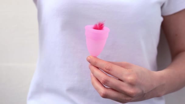 Las manos femeninas muestran el uso de copa menstrual con pluma roja. Mano de mujer sosteniendo copa menstrual. Higiene íntima femenina período cero productos de desecho. Concepto de salud femenina. — Vídeo de stock