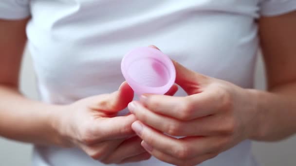 Las manos femeninas muestran el uso de copa menstrual. Mano de mujer sosteniendo copa menstrual. Higiene íntima femenina período cero productos de desecho. Concepto de salud femenina. — Vídeos de Stock