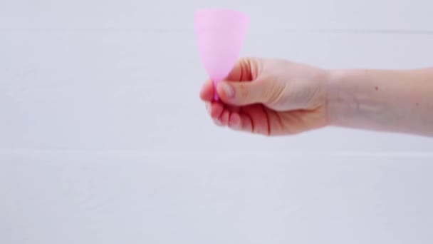 Donna mano che tiene la tazza mestruale. Le mani femminili mostrano utilizzando tazza mestruale su sfondo bianco. Periodo di igiene intima femminile zero rifiuti prodotti. Concetto di salute femminile. — Video Stock