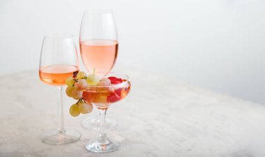 Rose wine in different wineglasses on white table with grapes. Wine composition on light concrete background. modern still life Long web banner with copy space