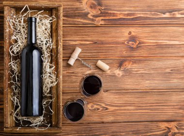 Red Wine composition on brown wooden table. Top view. Red wine bottle corkscrew corks wine glasses on wooden table with copy space.