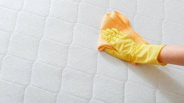 Employee cleans surface of mattress on bed with rag. Cleaning disinfection surfaces. Cleaning company person Hand in glove do Mattress chemical cleaning. Long web banner with copy space