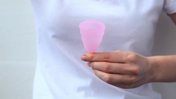 Női kéz fogja a menstruációs csészét. A női kezek mutatják a menstruációs csésze piros toll vér szimbólum. Női intim higiéniai időszak nulla hulladék termékek. A nők egészségének fogalma. — Stock videók