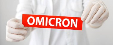 Omicron kırmızı uyarı işareti. Yeni Omicron varyantı Cavid 19 beyaz önlüklü ve eldivenli doktorların elinde. Uzun web pankartı