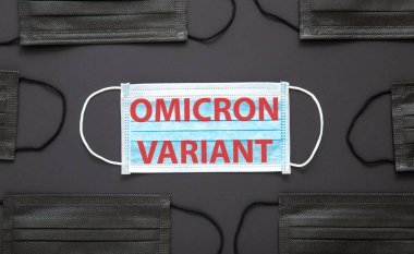 Yeni Omicron varyasyon covid 19 metin yüz maskesi üzerinde siyah arkaplanda izole. Tıbbi koruyucu siyah maske üzerinde Omicron pozitif mesaj uyarısı işareti.