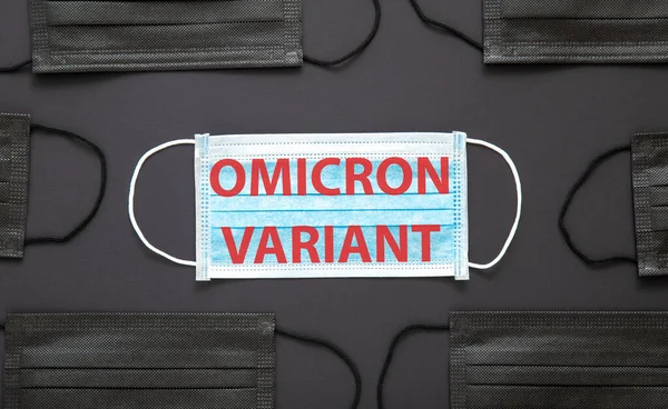 Yeni Omicron varyasyon covid 19 metin yüz maskesi üzerinde siyah arkaplanda izole. Tıbbi koruyucu siyah maske üzerinde Omicron pozitif mesaj uyarısı işareti.