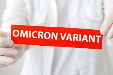 Kırmızı uyarı işareti yazılı Omicron varyantı metin. Yeni Omicron varyantı covid 19 beyaz önlüklü ve eldivenli doktorun ellerinde..