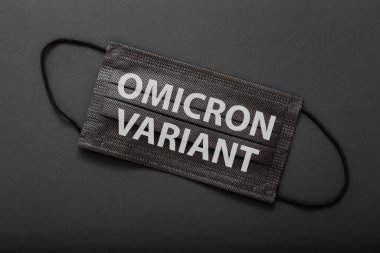 Tıbbi koruyucu siyah maske için Omicron 'a mesaj geldi. Yeni Omicron değişkeni covid 19 yüz maskesi üzerinde siyah arkaplanda izole.