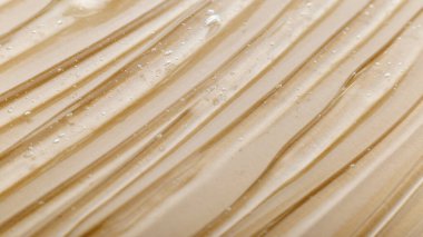 Bej rengi açık renk arka planda kozmetik nemlendirici ürünün berrak sulu jel dokusu. Hyaluronik asit jeli ya da deri tonunda kolajen arkaplan dokusu. Serum yüzeyi. Uzun web pankartı