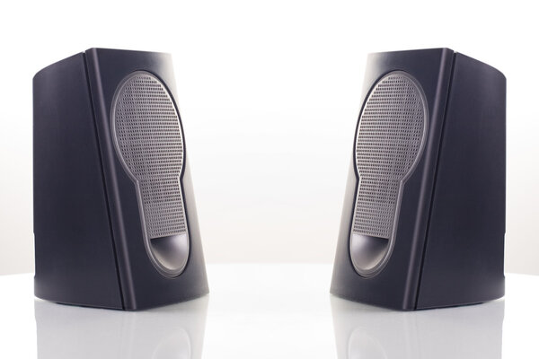 Two computer speakers, with a reflection on white background.