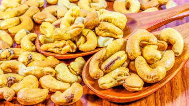 Ahşap kaşıkta kavrulmuş kaju fıstığı. Beyaz arka planda kavrulmuş tuzlu kaju fıstığı. Sağlıklı yiyecekler, kaju fıstıkları kalp dostu yağ asitleri bakımından zengin. Fıstıklı fındık..