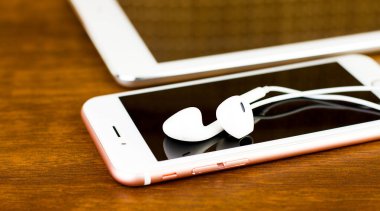Kulaklıklı bir tahta üzerinde tablet ve akıllı telefon.