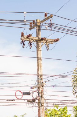 Elektrik kabloları, trafo kabloları ve telefon hatlarıyla, Asya 'nın başkenti Tayland' da bulunan parlak mavi gökyüzüne karşı yolda beton elektrik pilonu ve teknolojisi yakın plan.