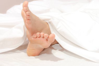 Under the covers with feet showing in a bed 