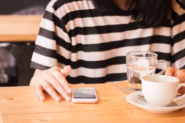Kadın akıllı telefonda sohbet ederken, kafede oturan, cep telefonu kullanan genç ve güzel bir iş kadını, akıllı telefon kullanarak bir masada oturan genç kadın....