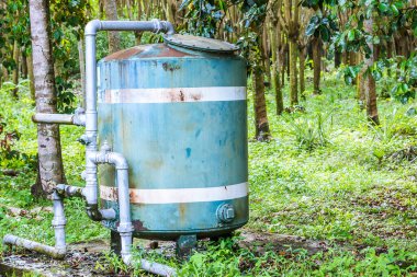 A close up of a rusted valve connects to water supply with metal pipe,Industrial metal water tab,seen in a garden, for watering the plants