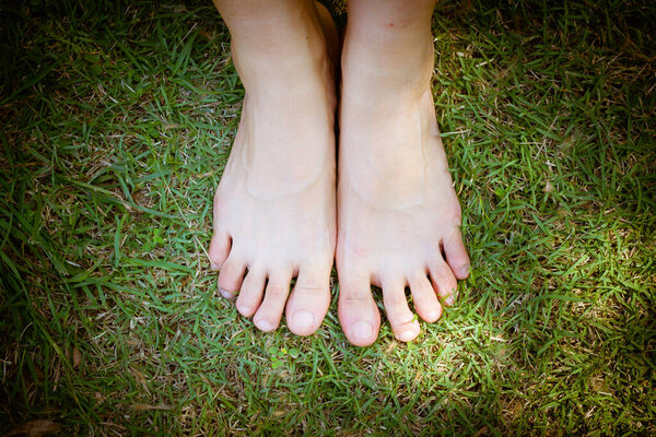 bare feet and hands with creative teens manicure and pedicure on the green grass lawn background,Foot over green grass