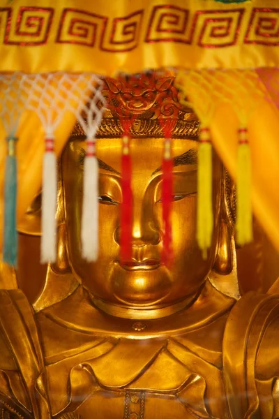 Estátua de ouro de Buda por trás borlas coloridas — Fotografia de Stock