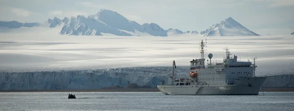 Uppblåsbar och vita fartyget bredvid is klippa — Stockfoto