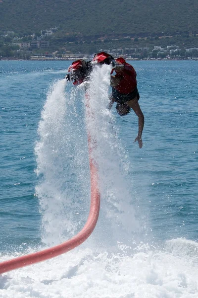 Flyboarder buceando en el agua seguido de una manguera —  Fotos de Stock