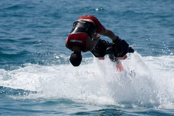 Flyboarder em vermelho mergulho headfirst em direção à câmera — Fotografia de Stock