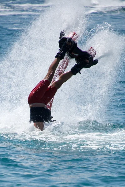 Flyboarder en rojo entrando en agua en spray —  Fotos de Stock