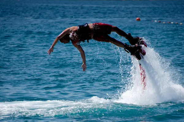 Flyboarder em vermelho torcendo horizontalmente em mergulho — Fotografia de Stock