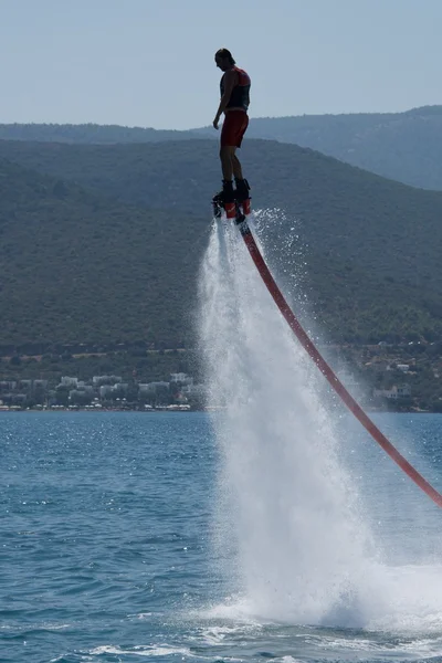 Flyboarder em silhueta balanceamento alto acima da água — Fotografia de Stock