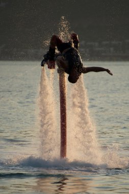 Flyboarder sprey tarafından çevrili ters parende yapıyor