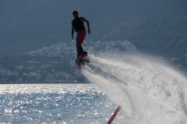 Arkadan aydınlatmalı deniz üzerine sprey tarafından takip Flyboarder