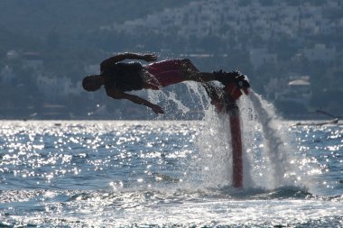 Flyboarder arkadan aydınlatmalı dalgaları içine dalış önce yatay