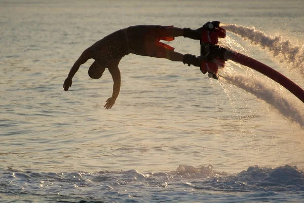 Primo piano di immersioni Flyboarder retroilluminato contro le onde — Foto Stock