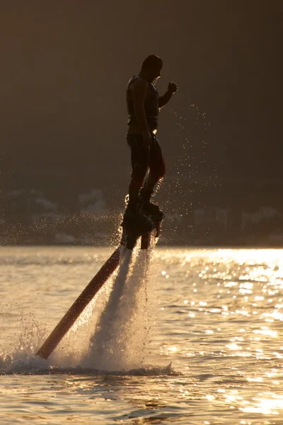 Flyboarder και το νερό σταγονίδια με οπίσθιο φωτισμό στο ηλιοβασίλεμα — Φωτογραφία Αρχείου