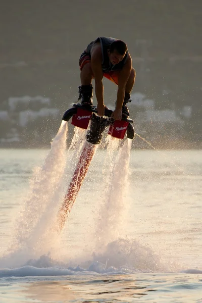 Flyboarder agachándose para agarrar el tablero al atardecer —  Fotos de Stock