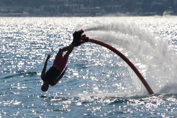 Flyboarder buceando hacia atrás de cabeza en el mar retroiluminado — Foto de Stock