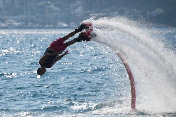 Flyboarder ダイビングはスプレーの円弧に続ける — ストック写真