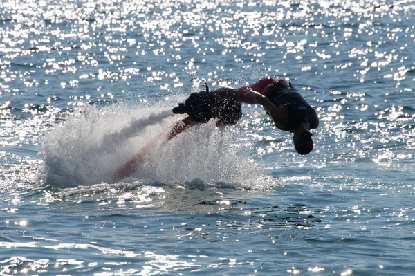 Flyboarder buceando hacia adelante de cabeza en el mar retroiluminado —  Fotos de Stock