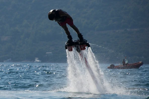 Flyboarder dykning huvudstupa med uppblåsbara i bakgrunden — Stockfoto