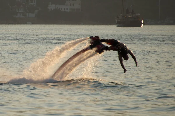 Flyboarder sumergirse en olas con yate detrás —  Fotos de Stock