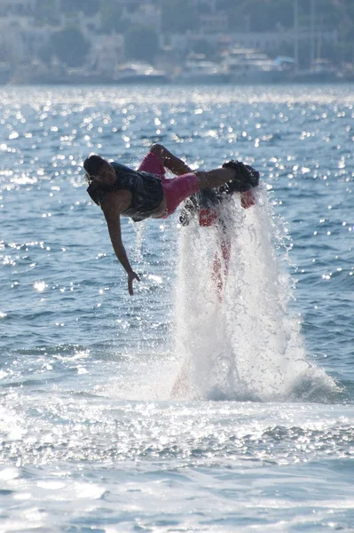 Flyboarder horizontal cayendo hacia atrás en olas retroiluminadas —  Fotos de Stock