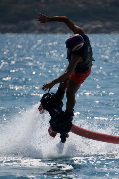 Flyboarder en el casco sumergiéndose en olas retroiluminadas —  Fotos de Stock