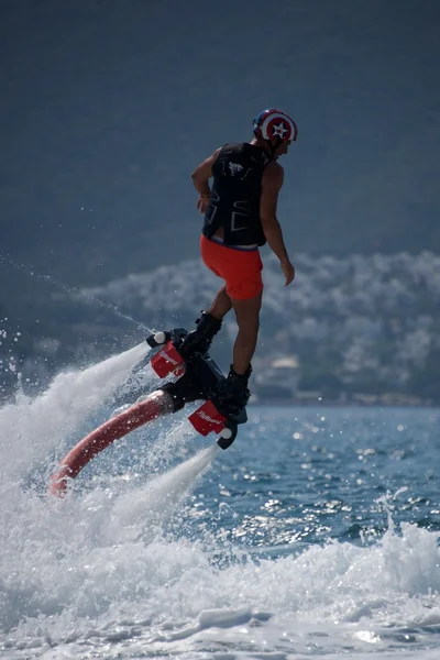 Flyboarder en casco volando por encima de burbujeante agua blanca —  Fotos de Stock