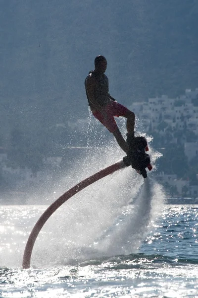 Flyboarder in silhouette a spirale sulle onde retroilluminate — Foto Stock