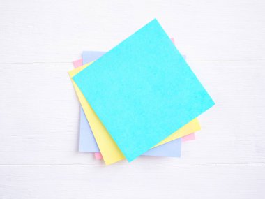 Yapışkan not (post-it) beyaz bir ahşap üzerine yığılmış. Mesajınız için boş alan ve şablon.