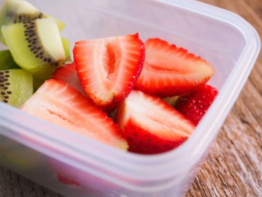 Yakın plan, çilek ve kivi tahta arka planda beyaz bir kutuda. Diyet yemek ve yüksek vitamin C, sağlıklı meyve.
