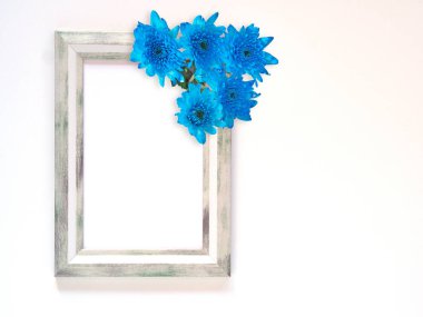 Grey rectangle border photo frame and blue flowers (chrysanthemum) on white background. Top view, flat lay with copy space